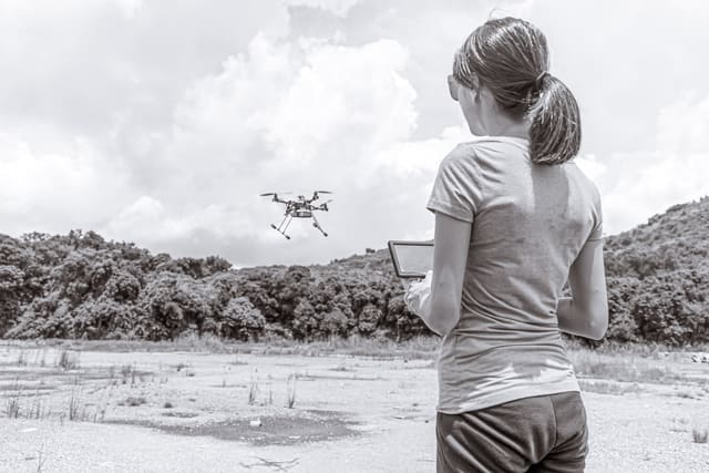 An operator flying a survey drone over open ground