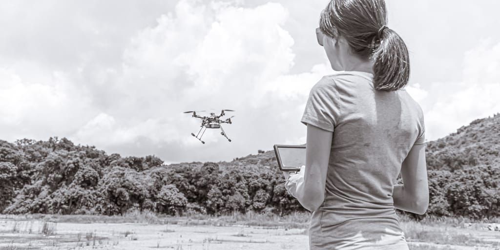 An operator flying a survey drone over open ground